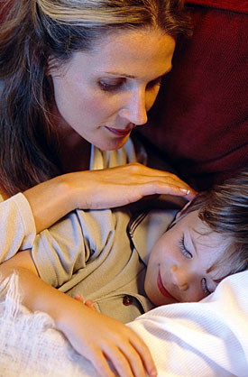 Mother tucking in child
